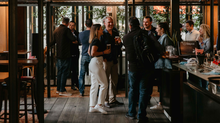 Busy atmosphere inside The General Assembly with patrons enjoying drinks and conversations at high wooden tables, showcasing the venue's suitability for daytime functions and social gatherings.