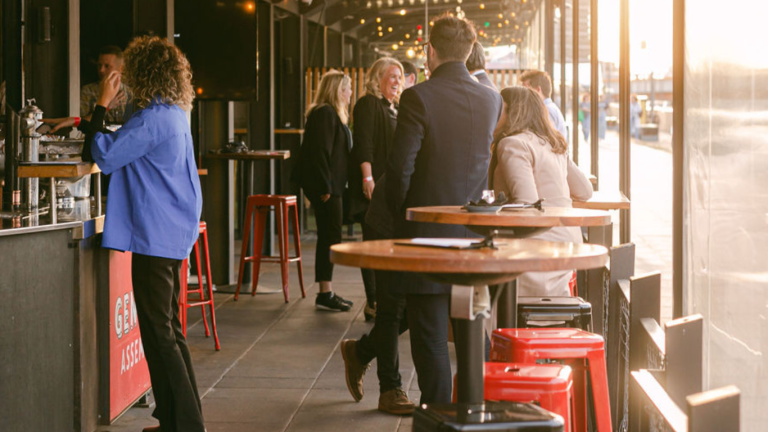 A lively scene inside The General Assembly with guests enjoying drinks and conversations, demonstrating the venue's capacity to host large indoor functions and social events.