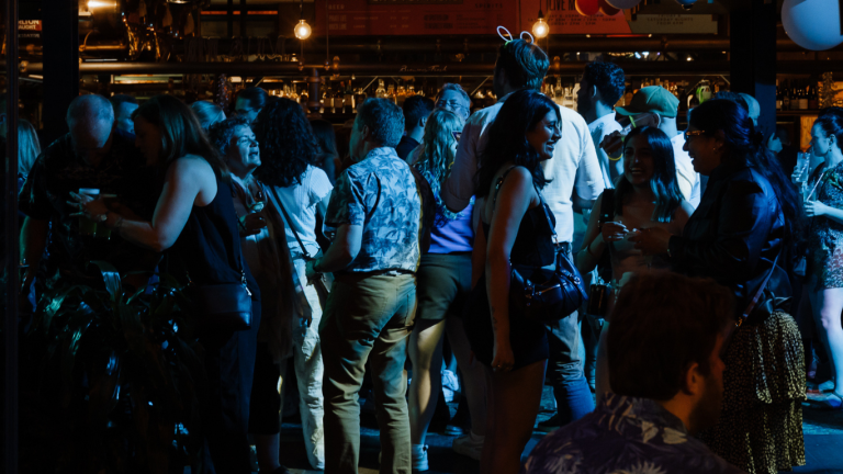 A busy night scene with a diverse crowd mingling both inside and outside, reflecting The General Assembly's popularity as a nightlife spot and function venue.